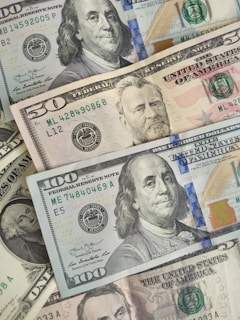 A collection of various denominations of United States currency, prominently featuring detailed images of historical figures on each bill.