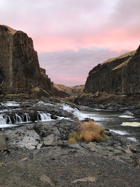 brown rock formation near body of water during daytime in Palouse Falls State Park United States