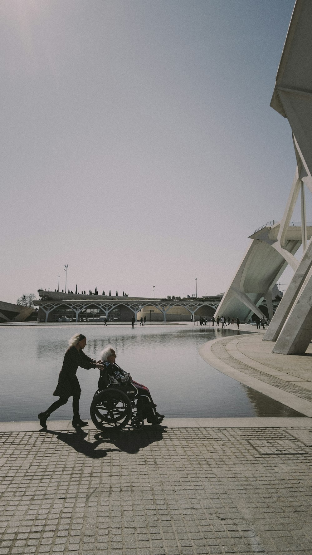 man in black jacket and black pants sitting on gray concrete bridge during daytime