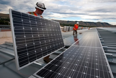 man in red shirt and black pants standing near solar panels during daytime solar google meet background