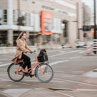woman in brown coat riding on black bicycle on road during daytime