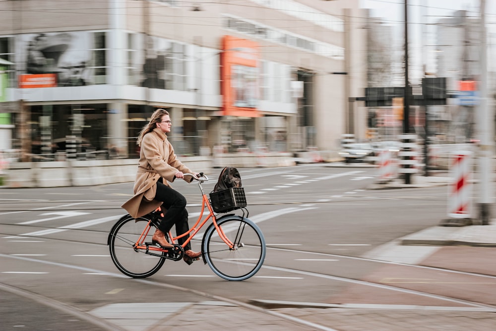 昼間、道路で黒い自転車に乗る茶色のコートを着た女性