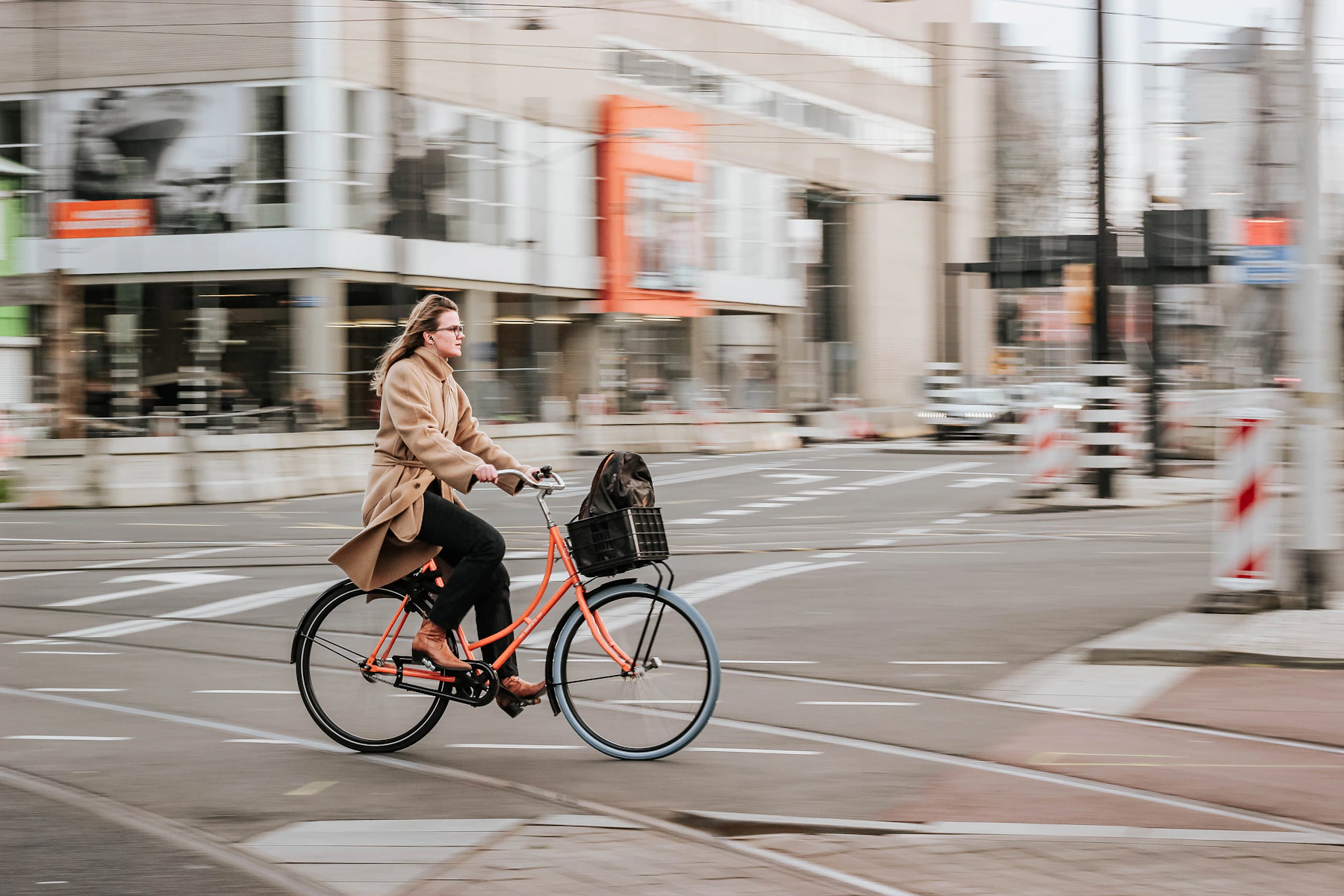 Mulher numa bicicleta urbana com cesta, em rua de cidade