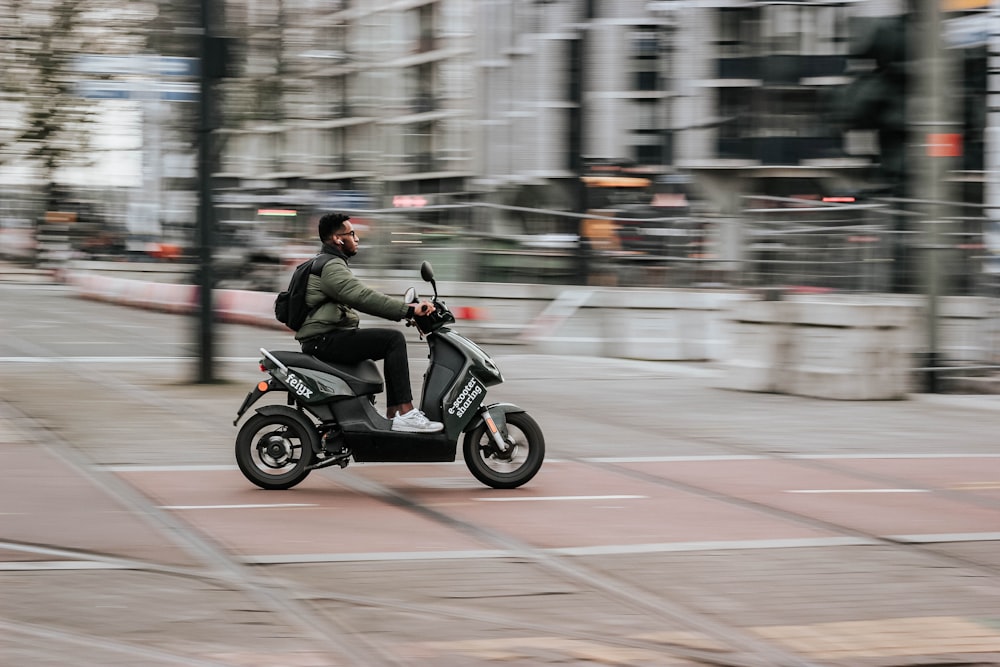 Mann in grüner Jacke fährt tagsüber Motorrad auf der Straße