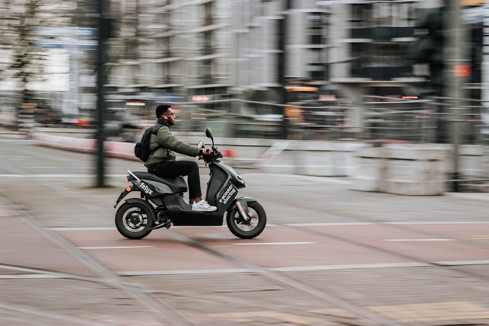 homme en veste verte conduisant une moto sur la route pendant la journée