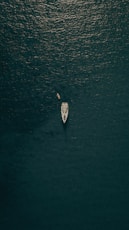 aerial view of person in white shirt riding on white boat on water during daytime