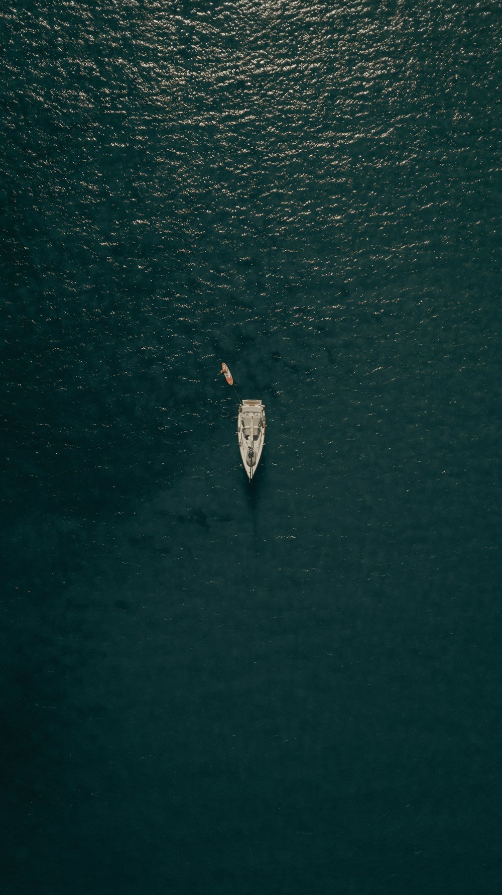 Luftaufnahme einer Person im weißen Hemd, die tagsüber auf einem weißen Boot auf dem Wasser fährt