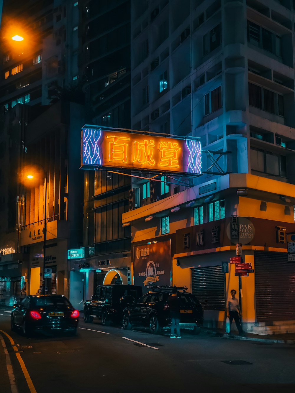 cars parked on the side of the road in front of the building during night time