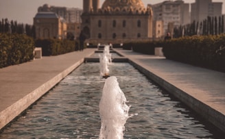 water fountain in front of brown dome building