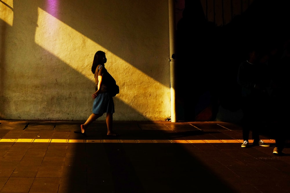 woman in black dress walking on sidewalk during daytime