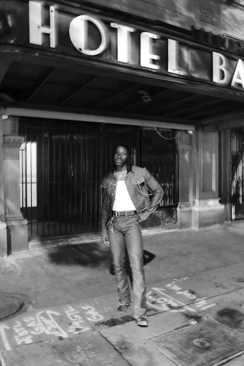 woman in white long sleeve shirt and blue denim jeans standing on sidewalk