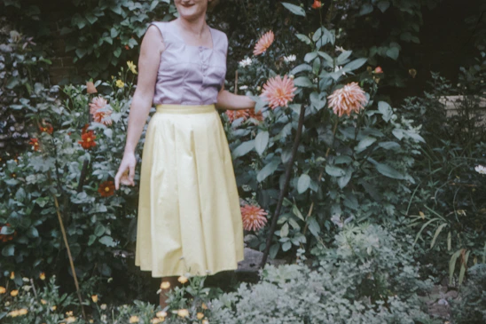 Lauren E. Gaskin smiling in her Louisiana garden, surrounded by blooming flowers and greenery.