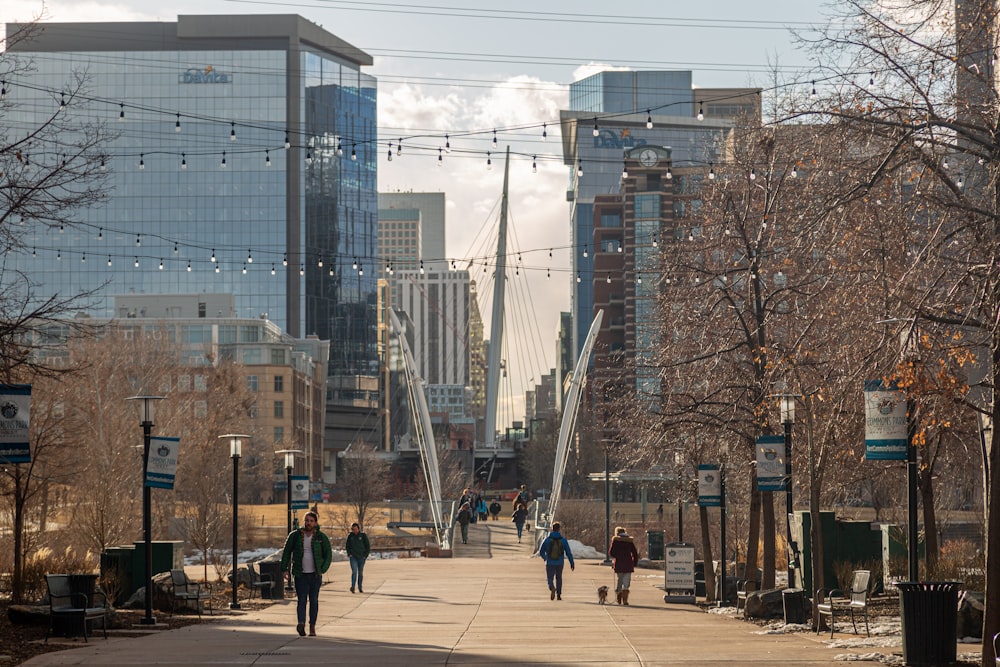 a group of people walking down a sidewalk next to tall buildings