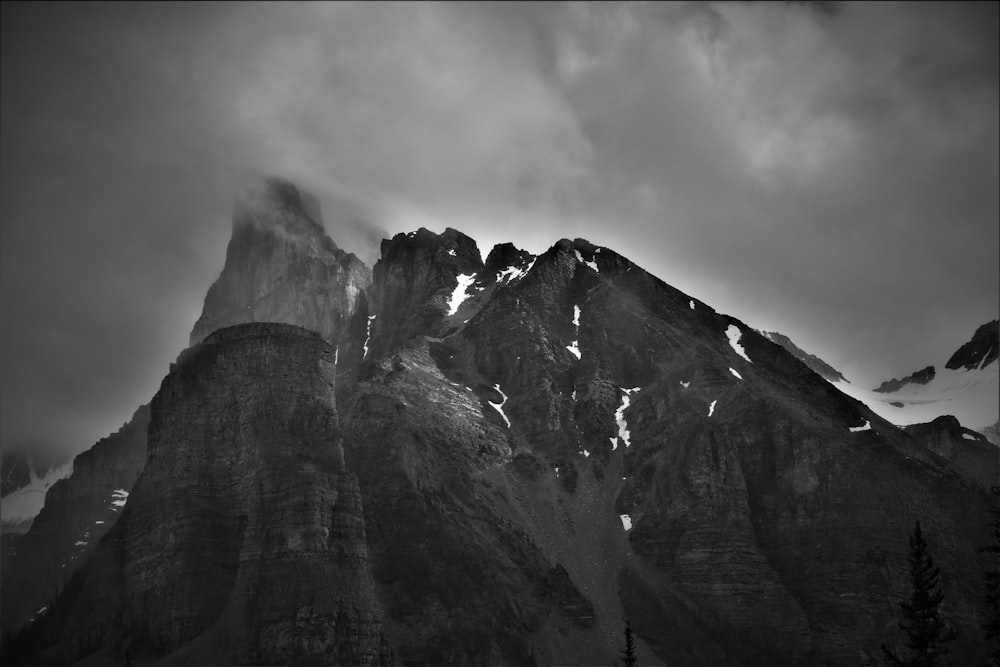 grayscale photo of rocky mountain under cloudy sky