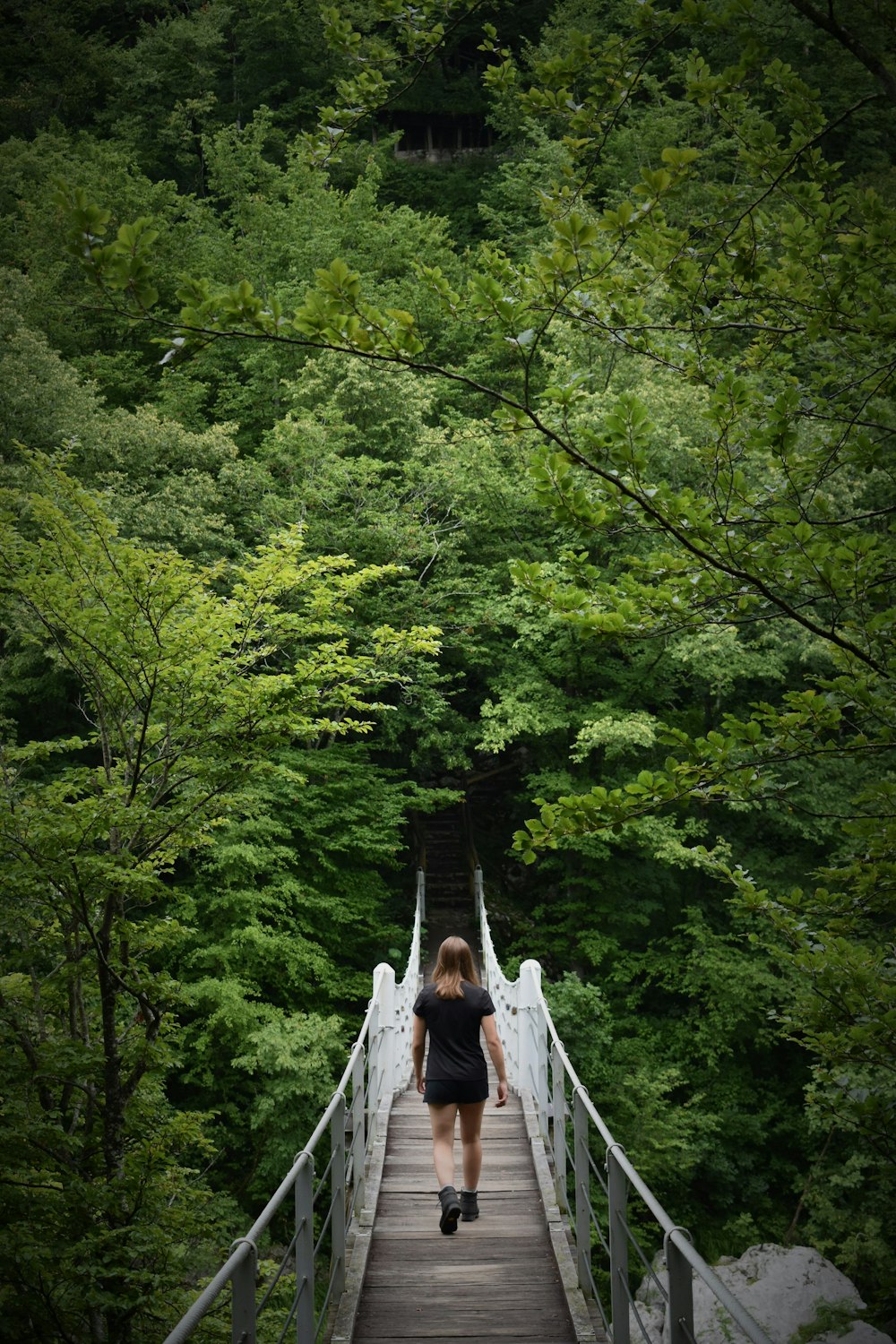 woman in white dress walking on hanging bridge