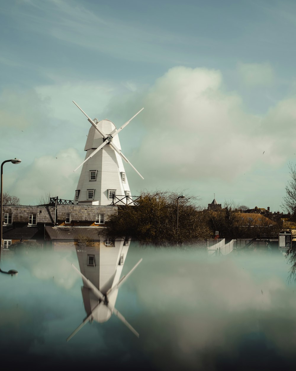 white windmill near body of water during daytime