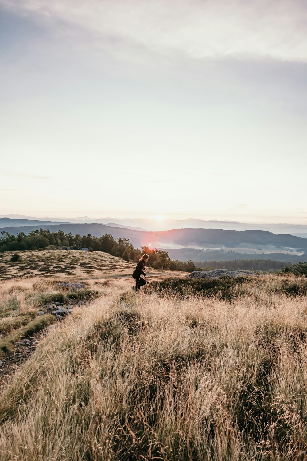 woman in black jacket walking on brown grass field during daytime