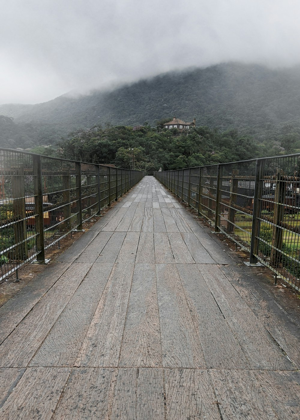 gray wooden pathway between green grass field during daytime