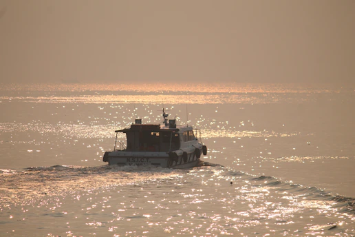 A close-up of a sleek electric boat gliding silently over calm Mediterranean waters at sunset.