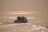 A serene boat gliding through calm waters at sunset.