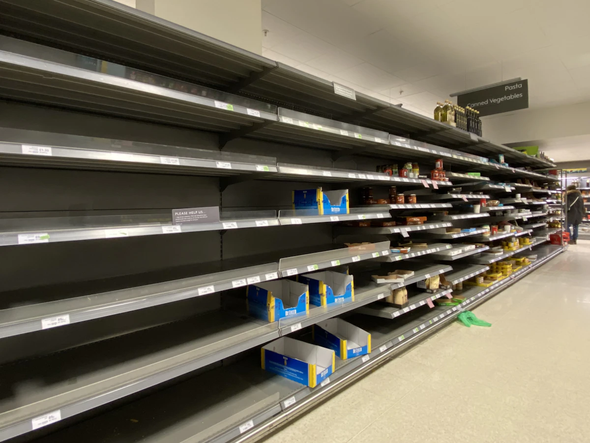 White and blue plastic bottle on sparse supermarket shelf — mostly empty grocery shelving
