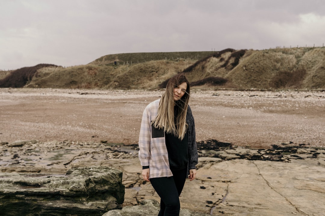 woman in white jacket standing on gray sand during daytime