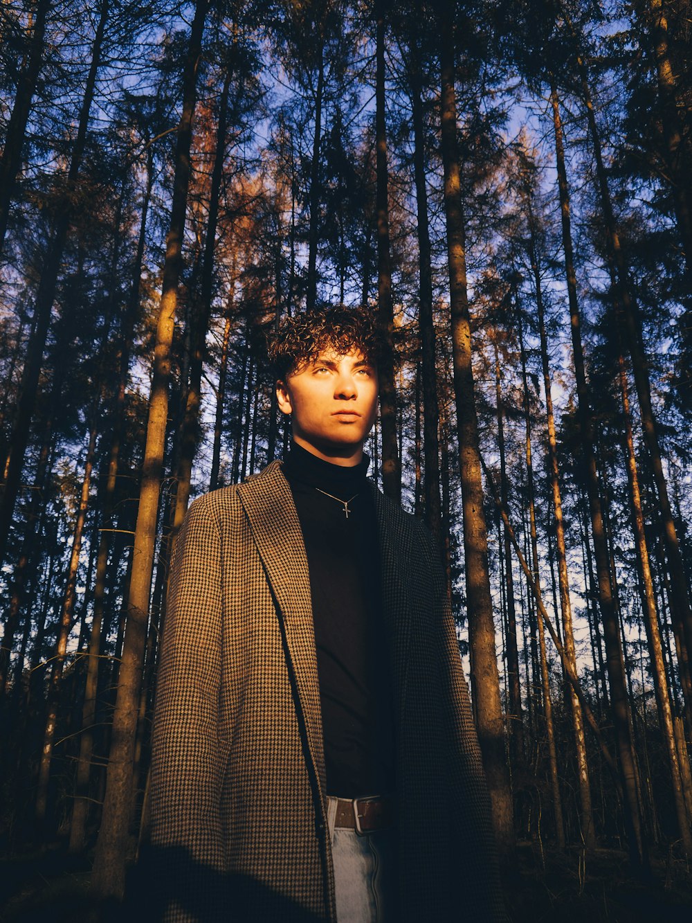 man in black suit jacket standing in forest during daytime