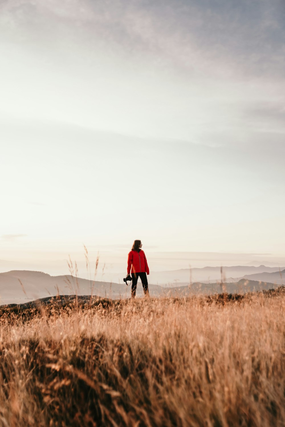 man in red jacket standing on brown grass field during daytime