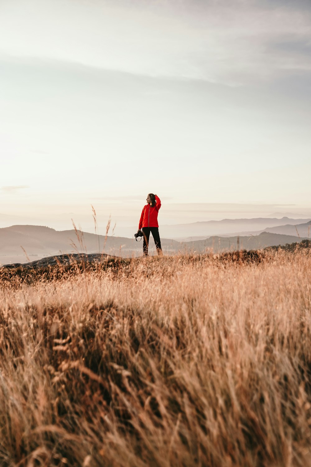 person in red jacket walking on brown grass field during daytime