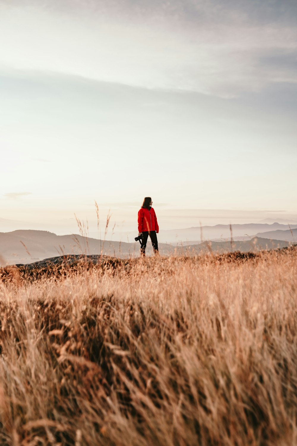 man in red jacket walking on brown grass field during daytime