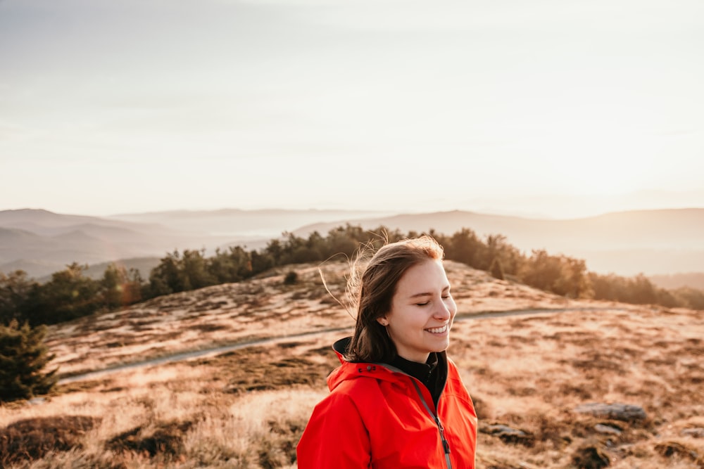 woman in red jacket standing on brown field during daytime