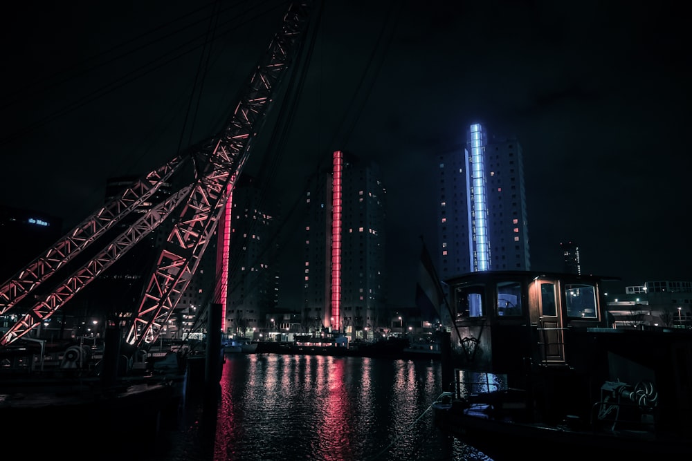 red metal bridge near city buildings during night time