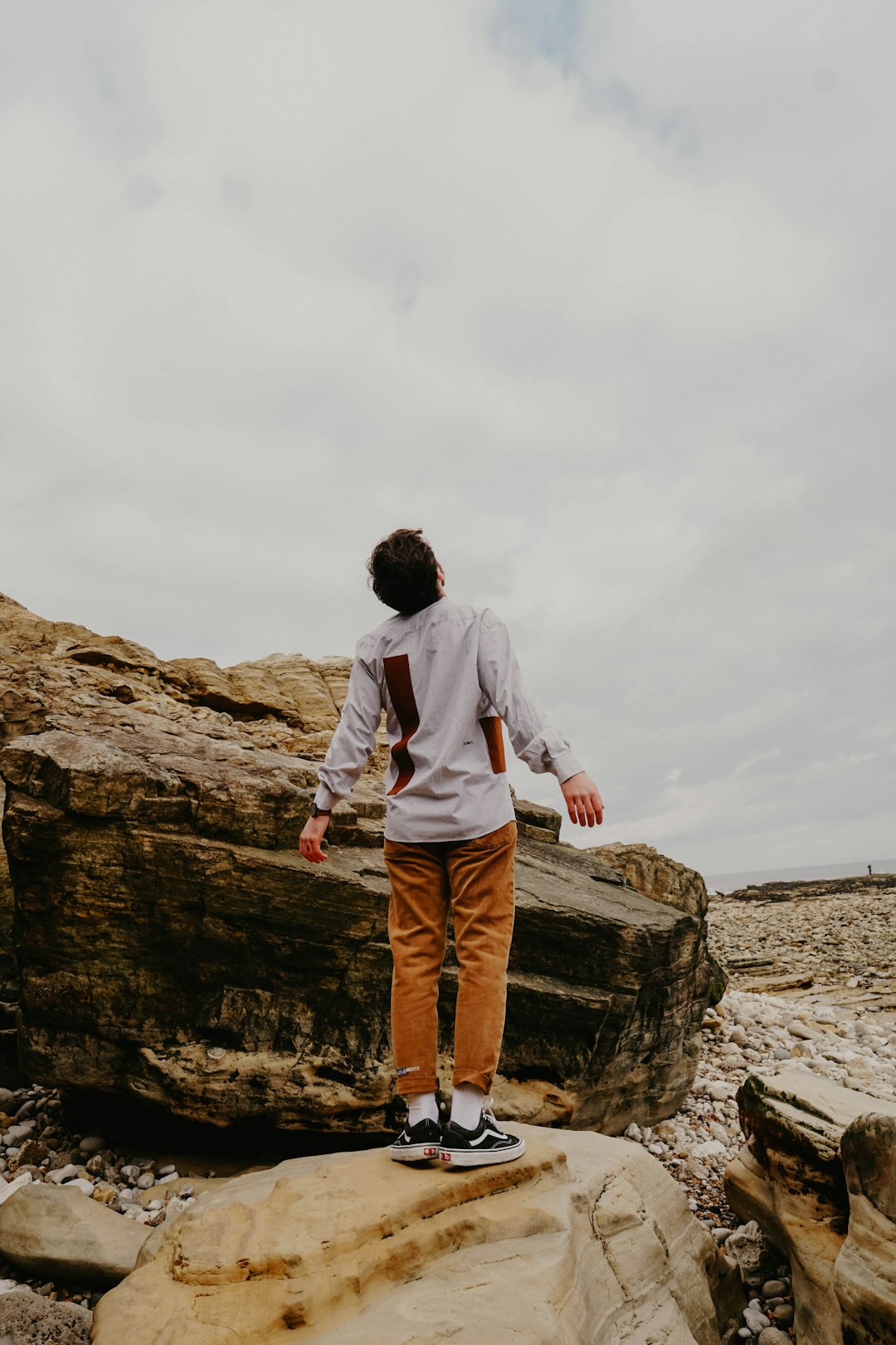 man in gray hoodie standing on brown rock formation during daytime