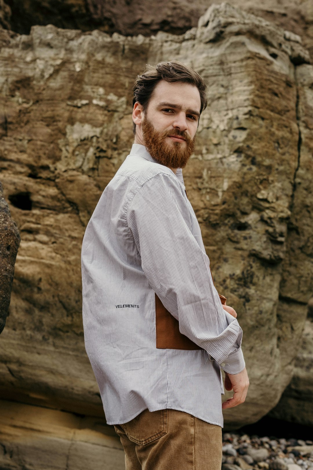 man in white dress shirt and white pants sitting on rock