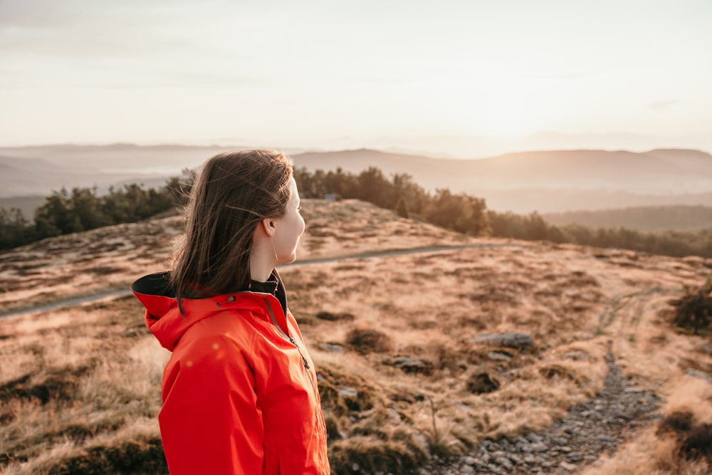 woman in red jacket standing on brown field during daytime