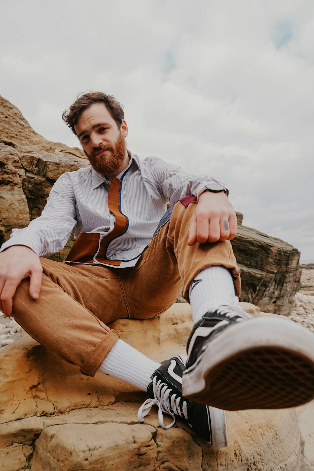 man in brown jacket sitting on brown rock during daytime