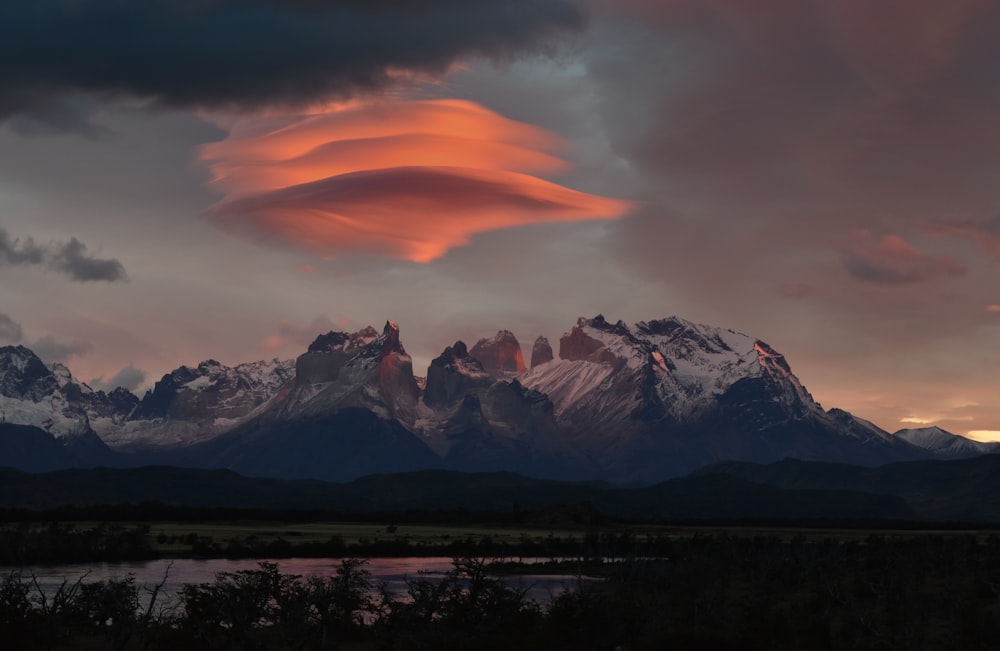 Montaña cubierta de nieve cerca del cuerpo de agua durante la puesta del sol