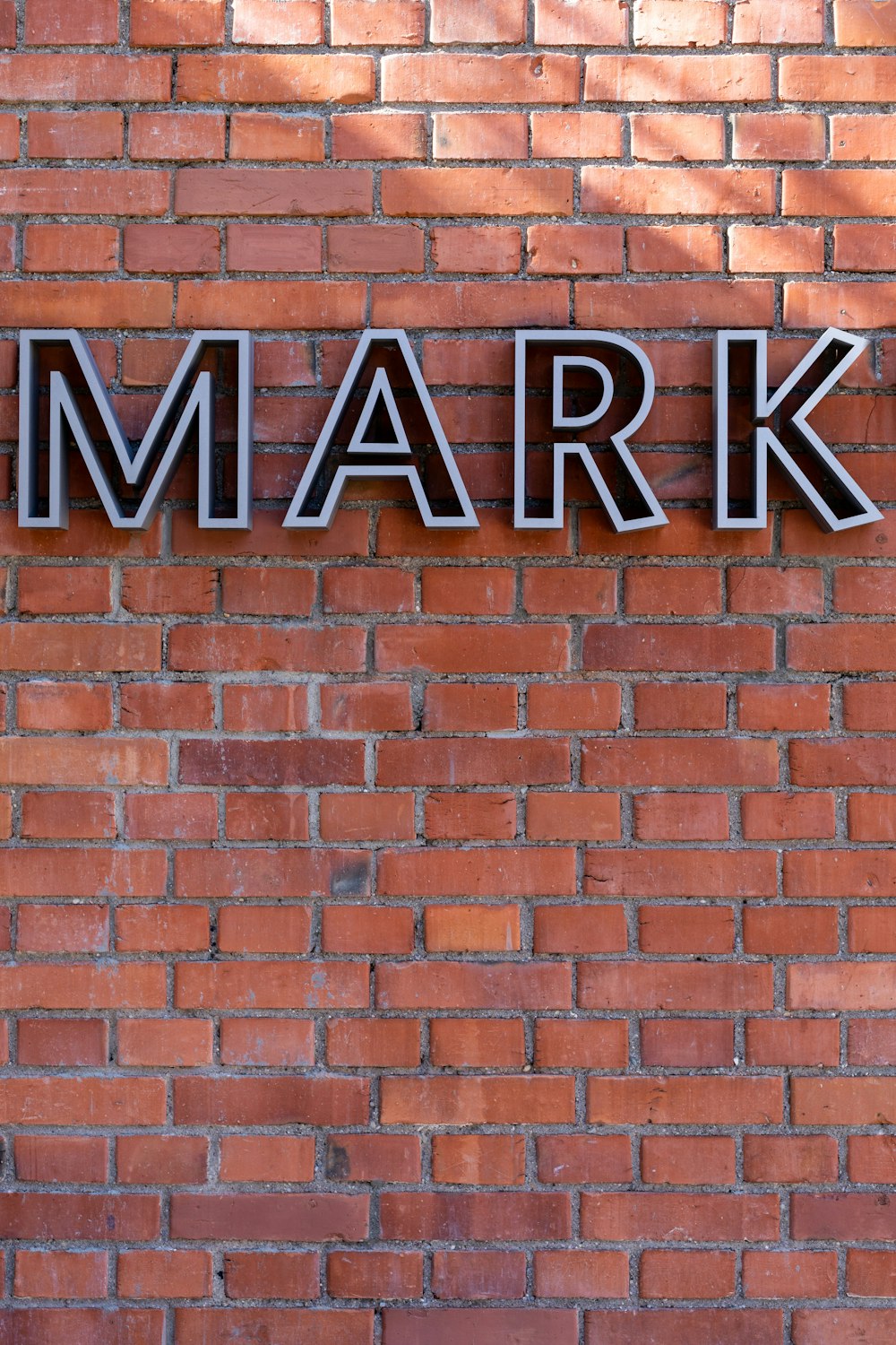 brown brick wall with black and white UNK sign