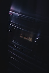 A vintage audio stereo system with a display screen showing text, illuminated in a dimly lit environment. The brand name Aiwa is visible at the top left corner, and the equipment has a sleek, reflective surface with buttons and a knob.