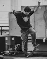 Dynamic shot of a skateboarder mid-trick wearing a dark oversized tee and cargo pants on urban pavement.