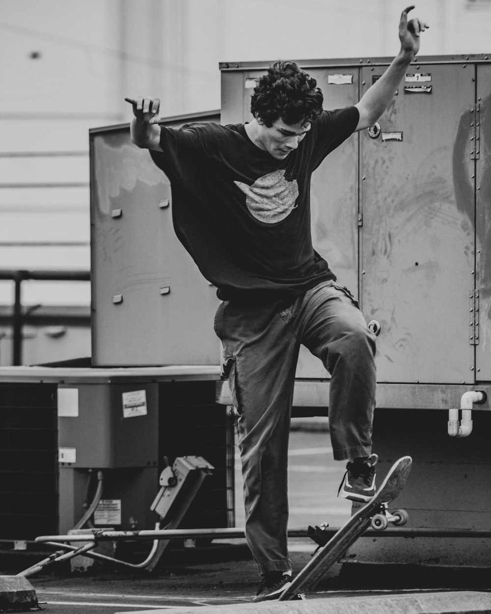 man in black t-shirt and gray pants riding skateboard in grayscale photography