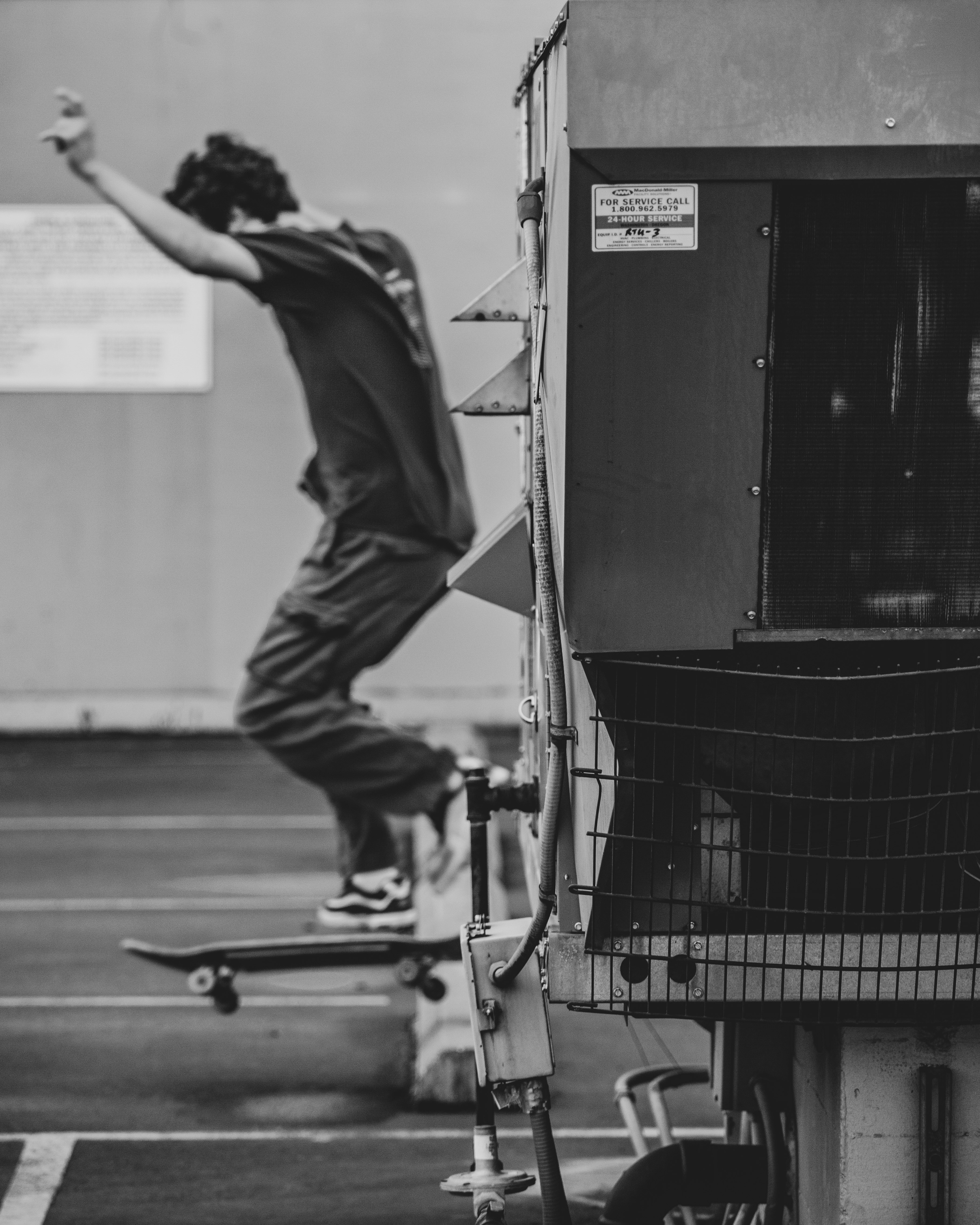 man in black t-shirt and pants riding on black skateboard in grayscale photography