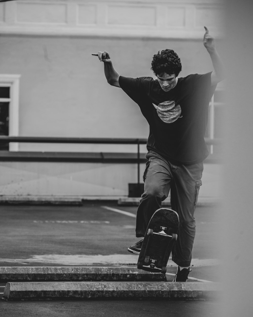 검은 긴 소매 셔츠와 바지를 입은 남자가 그레이스케일 사진에서 스케이트보드에 앉아 있다