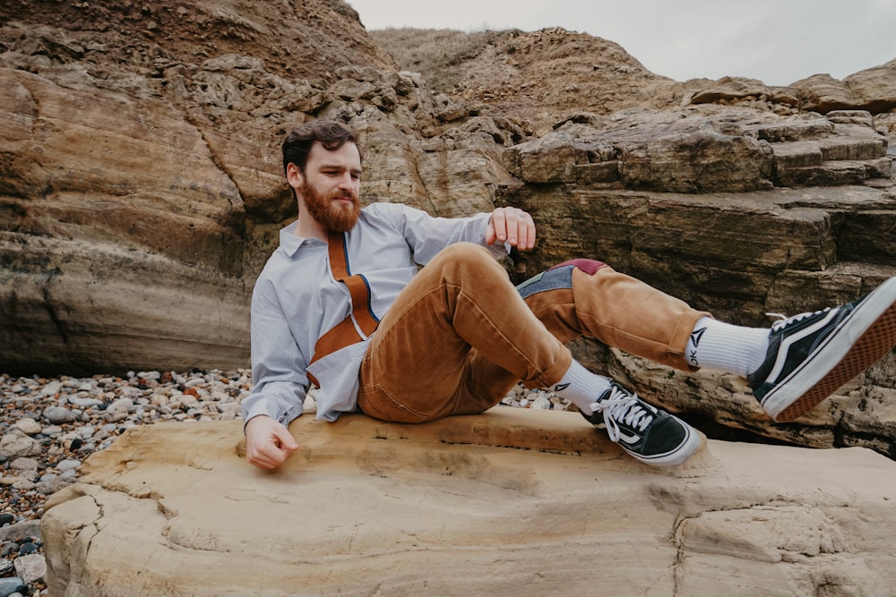 man in brown pants sitting on brown rock during daytime