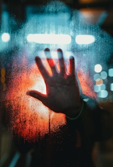 person in black long sleeve shirt with water droplets on glass
