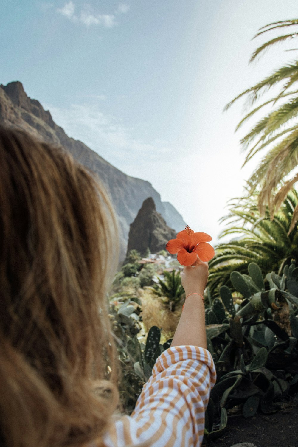 woman in white and red plaid long sleeve shirt holding red flower