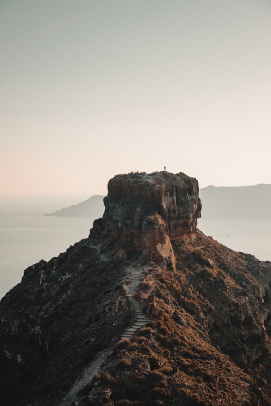 brown rock formation on sea during daytime in Thira Greece