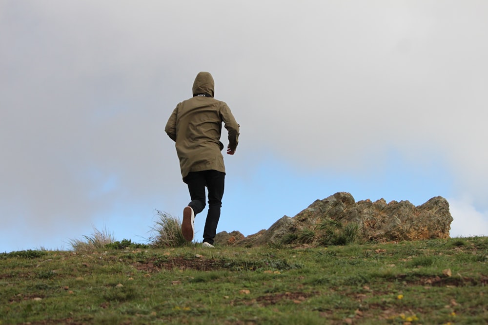 person in brown hoodie standing on green grass field during daytime