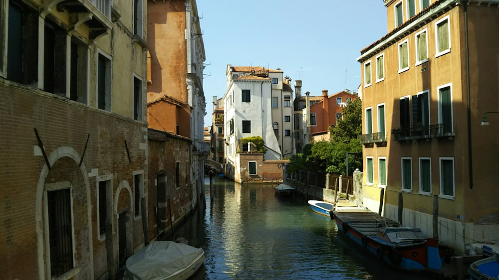 white boat on river between concrete buildings during daytime