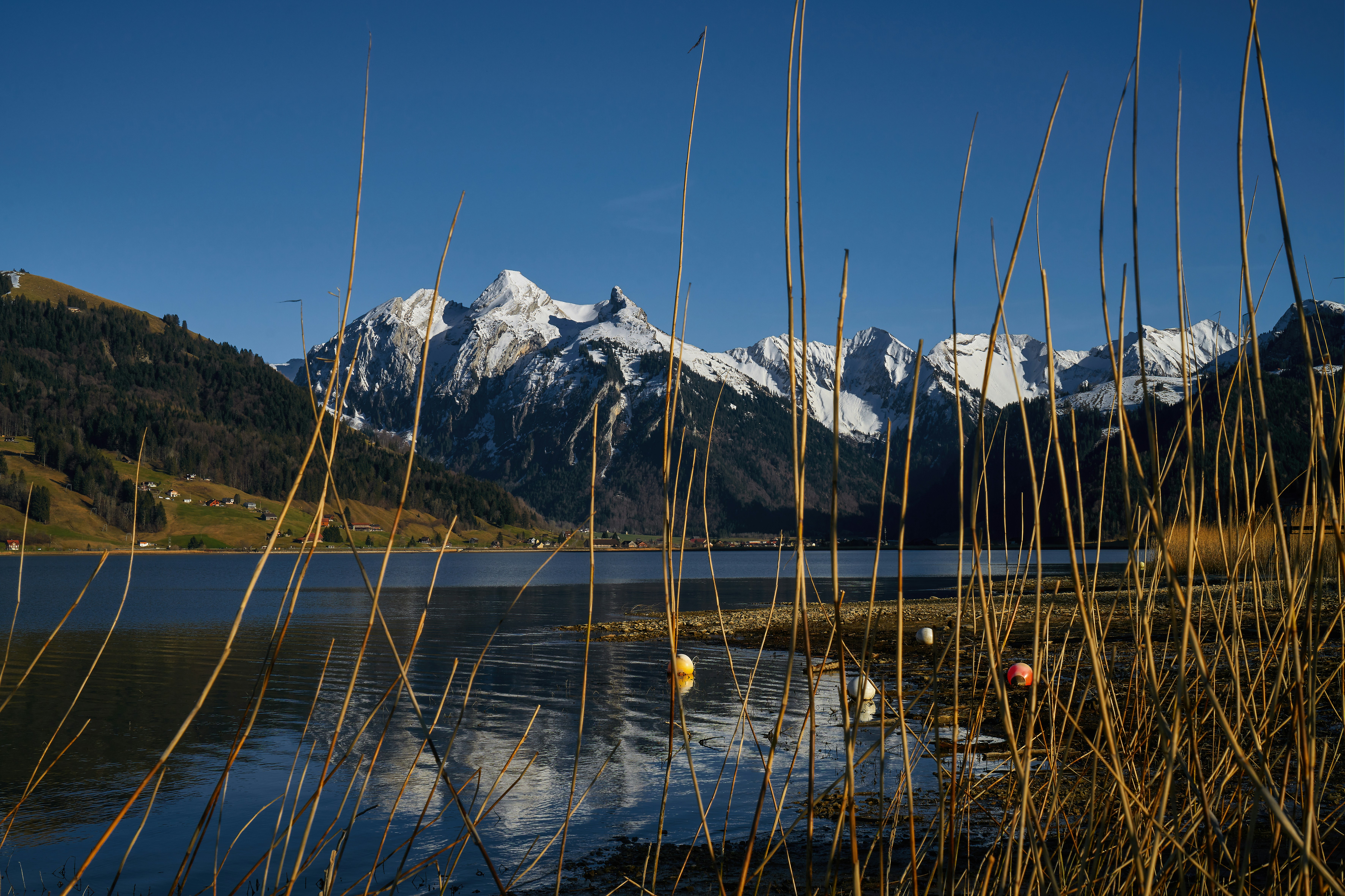 body of water near mountain under blue sky during daytime